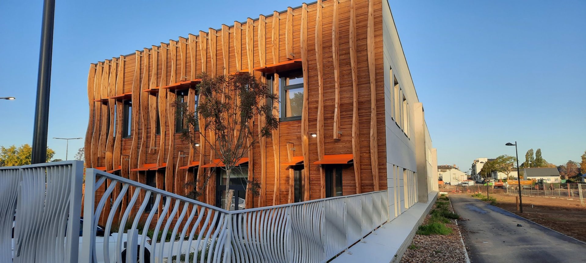 Revêtement minéral sur rue et bardage bois sur le cœur du site <br/> Crédit photo : Patrice Micheau Atelier M architectes